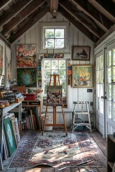 an artist's studio with lots of paintings on the walls