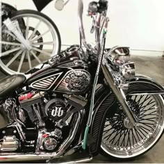 a black motorcycle parked in a garage next to two bikes on the ground and one has chrome spokes