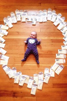 a baby is laying on the floor surrounded by stacks of money and envelopes that have been arranged into a heart shape