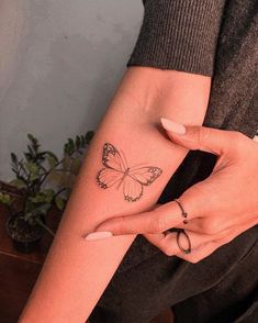 a woman's hand with a butterfly tattoo on her left arm and the wrist