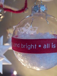 a christmas ornament hanging from a tree with snow on it and a red ribbon that says grand bright all is