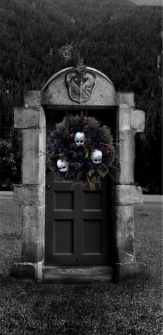 a black and white photo of an entrance to a cemetery with two skulls on it