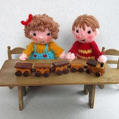 two knitted children's toys are sitting on a table with a toy train