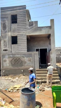 two men are standing in front of a building under construction with buckets on the ground