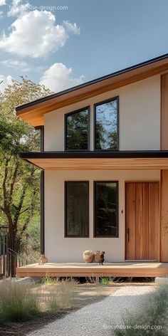 a modern house with wooden doors and windows on the front porch, surrounded by trees