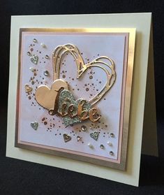 a greeting card with two hearts and the word love spelled in gold foil on it