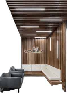 an empty waiting area with two chairs and a couch in front of a wooden paneled wall