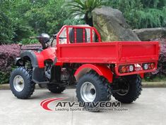 a red four wheeler truck parked in front of some bushes