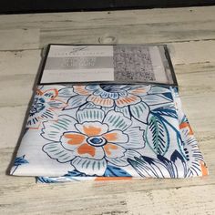 an orange, blue and white flowered cloth on a wooden table with the packaging