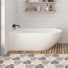 a white bath tub sitting on top of a wooden floor next to a brick wall