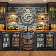 a large clock mounted to the side of a wall next to a wooden barrel filled with liquor