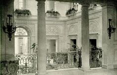 an old black and white photo of the inside of a building with columns, chandeliers and windows