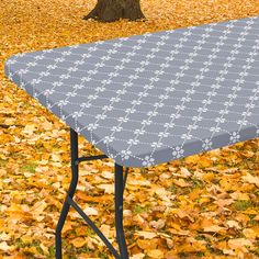 an ironing board sitting on top of a table covered in leaves next to a tree