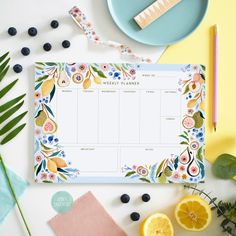 a table with lemons, blueberries and other fruits on it next to a planner