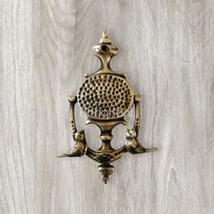 an ornate brass wall mounted hook with birds on it's face and the word,