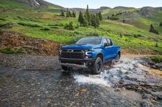 a blue truck is driving through some water