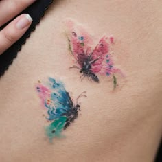 a woman's stomach with two butterflies painted on the back of her belly,