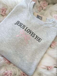 Welcome to our Etsy shop and check out our website www.ShopRusticHills.com. Wrap yourself in both comfort and inspiration with our "Jesus Loves You" embroidered sweatshirt, featuring a delicate pink bow detail. Crafted with care, this cozy sweatshirt is perfect for those seeking to share their faith in style. Whether it's for yourself or as a thoughtful gift, this sweatshirt is a beautiful reminder of love and grace. Available in various sizes and colors to match your unique look! Shipping Policy: We are not responsible for lost nor stolen packages once handed off to UPS or USPS, but we will help. They will have to get up with the carrier if a problem comes up. Pearl Stitch, Jesus Sweater, Christian Clothing Brand, Inspire Bible, Jesus Clothes, Bow Embroidery, Tee Ideas, Jesus Sweatshirts, Hoodie Ideas