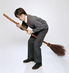 a young man holding a broom while standing on it's hind legs in front of a white background