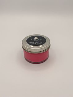 a red candle with a silver lid on a white surface