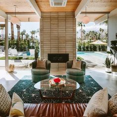 a living room filled with furniture and a fire place in front of a swimming pool