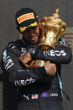 a man holding a trophy in his right hand and wearing a hat on top of him