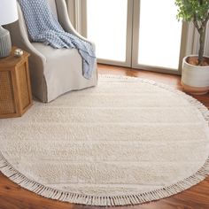 a white rug with fringes on the floor in front of a chair and window