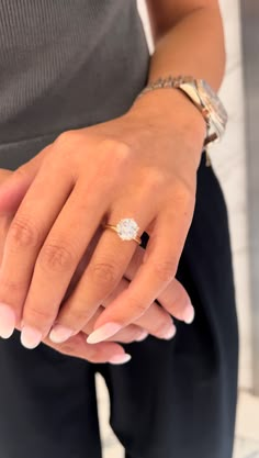 a woman's hand with a diamond ring on her left wrist and the other hand holding an engagement ring