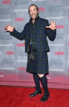 a man in a kilt poses on the red carpet at game of thrones