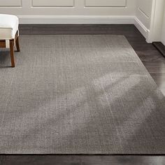 a gray rug with a white chair in front of it on a wooden floor next to a door