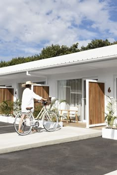 a man riding a bike in front of a white building