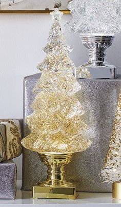 a christmas tree sitting on top of a table next to two presents and a vase