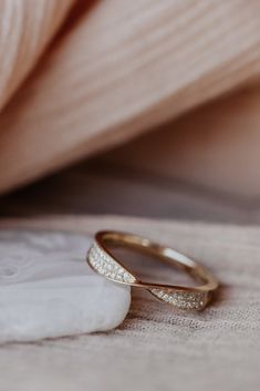 two gold wedding rings sitting on top of a white piece of cloth next to each other