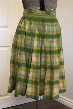 Just an absolutely gorgeous, classic 1950s circle skirt made of a substantial, quality wool fabric in shades of green, yellow, beige and tan. Pleated waist. Closes with two grey moonglow buttons and a small metal Lightning zipper. Forms a full circle. Falls to about mid-calf. No label, appears to have been homemade, but made very well. Condition: very good. It has one small hole on the back which I darned, see last photo. I am not the world's best seamstress, so you may prefer to redo it, but at Retro Green A-line Skirt, Green Accordion Pleats Skirt, Fitted Green Accordion Pleated Skirt, Vintage Full Pleated Skirt For Fall, Retro Green Skirt For Fall, Vintage Full Skirt With Accordion Pleats, Vintage Plaid Full Skirt, Retro Green Pleated Skirt, Vintage Pleated Plaid Skirt