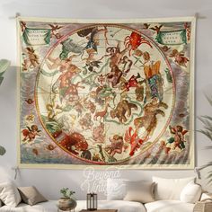 a large tapestry hanging on the wall in a living room with white couches and pillows