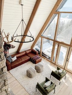 a living room filled with lots of furniture next to a tall window covered in snow