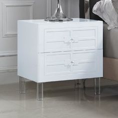 a white night stand with two drawers and a lamp on top