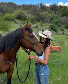 a woman standing next to a horse wearing a cowboy hat