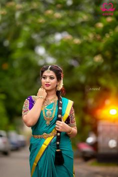 a woman in a green and yellow sari is talking on her cell phone while walking down the street