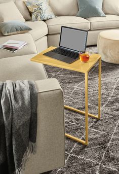 a laptop computer sitting on top of a wooden table in front of a white couch