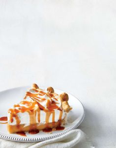 a slice of cheesecake with caramel drizzled on top is sitting on a white plate