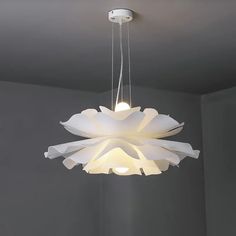 a white chandelier hanging from the ceiling in a room with gray walls and flooring