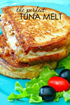 a grilled cheese sandwich with lettuce, tomatoes and olives on a blue plate