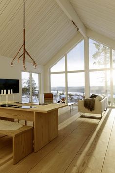 a large open living room with wooden floors and white walls, along with windows overlooking the water