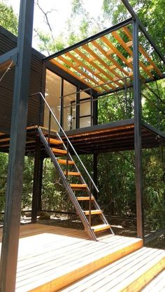 a wooden deck with stairs leading up to a small house in the middle of trees