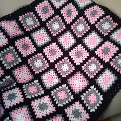 a crocheted blanket with pink and gray squares