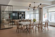 a large dining room table and chairs in front of a window with glass doors on both sides