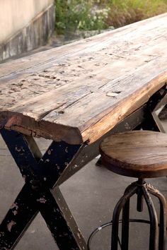 an old wooden table with two stools next to it and grass in the background