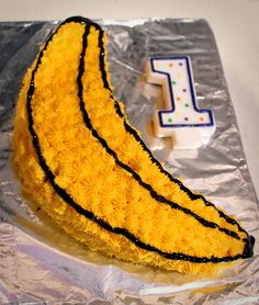 a birthday cake made to look like a banana on tin foil with the number 1