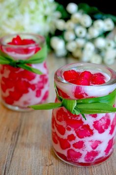 two jars filled with raspberry jello sitting on top of a wooden table